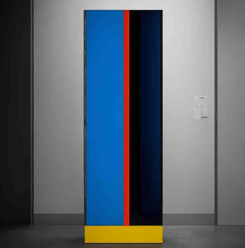 A tall sculpture in blue and red with a black base in a Pop-Up Gallery, showcasing a unique blend of colors and forms.