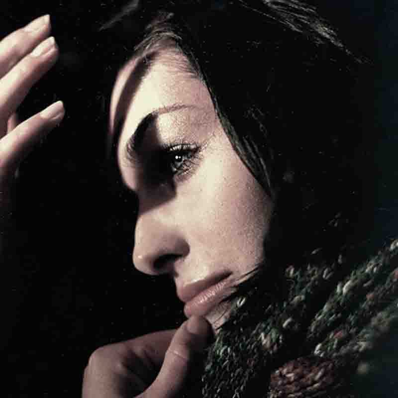Fashion photograph of a woman with dark hair and a scarf, exuding elegance and style.