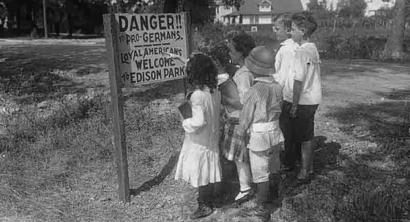 Children standing in front of an anti-German sign