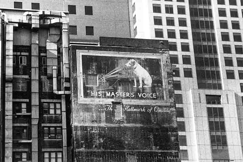 His Master's Voice billboard against the backdrop of a city building.