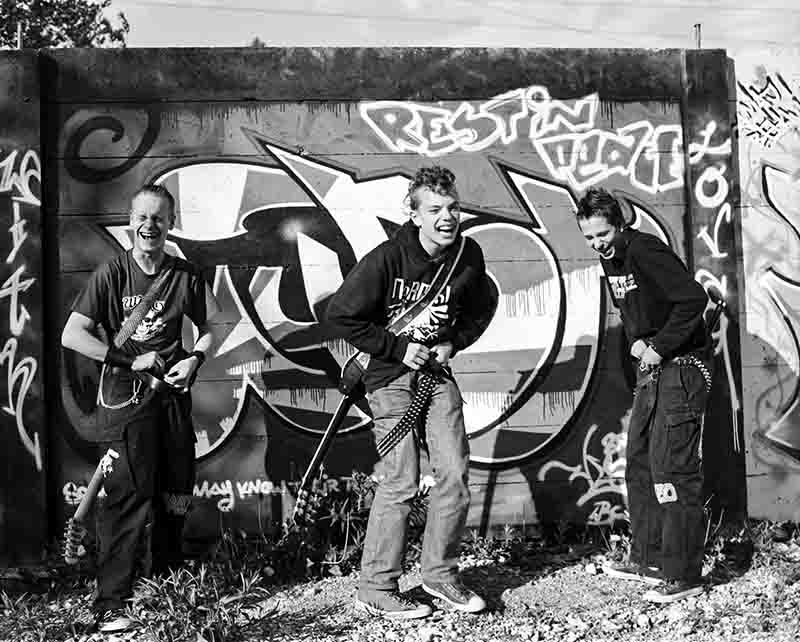 Three punk rockers posing in front of a vibrant graffiti wall, showcasing urban art and individuality.