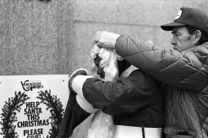 A man helping Santa Claus in New York to get dressed.