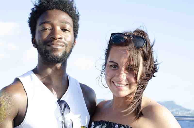 A couple smiling for a photo on a boat deck, enjoying a sunny day on the water during a Ibiza boat party