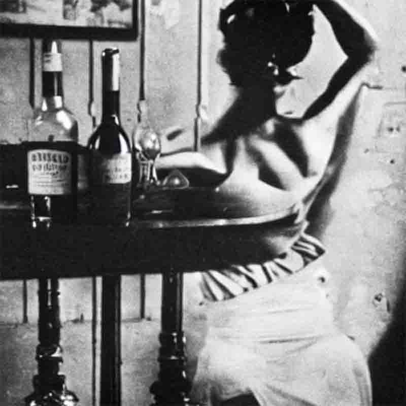 In this moody, expressionistic image titled wine woman song, a model stands defiantly in a Parisian Bar. She is dressed in a boudoir aesthetics outfit